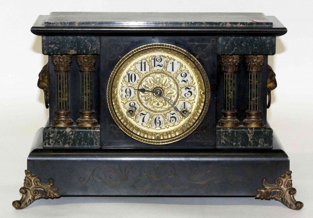 A Seth Thomas Ebonized and Faux Marble Mantel Clock,: A Seth Thomas Ebonized and Faux Marble Mantel Clock, of temple form, having a circular dial with Arabic numerals, further set with lion mask ring handles. Width 16 1/2 inches. Property from the Collec