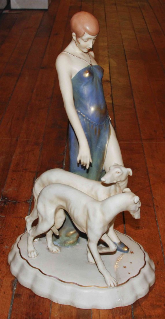 A Royal Dux Bisque Figural Group, Height 15 inches.: A Royal Dux Bisque Figural Group, depicting a Deco maiden with two hounds. Height 15 inches.