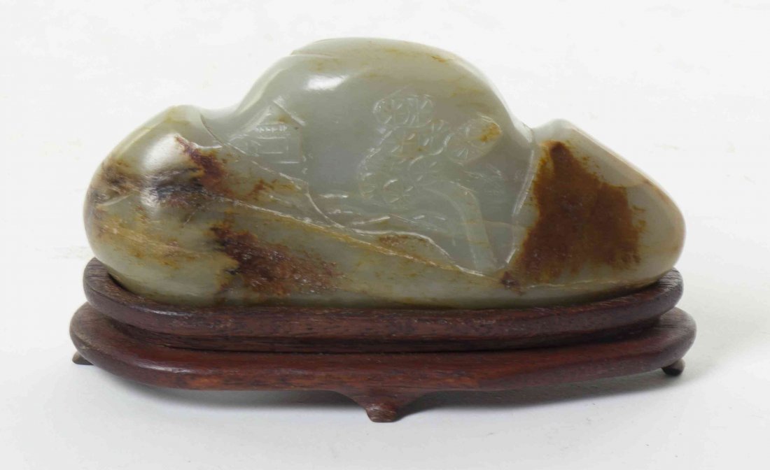 A Chinese Carved Jade Boulder, Width 4 1/8 inches.: A Chinese Carved Jade Boulder, of naturalistic form centered with carvings of a structure in a wooded landscape, set on a fitted wood base. Width 4 1/8 inches.