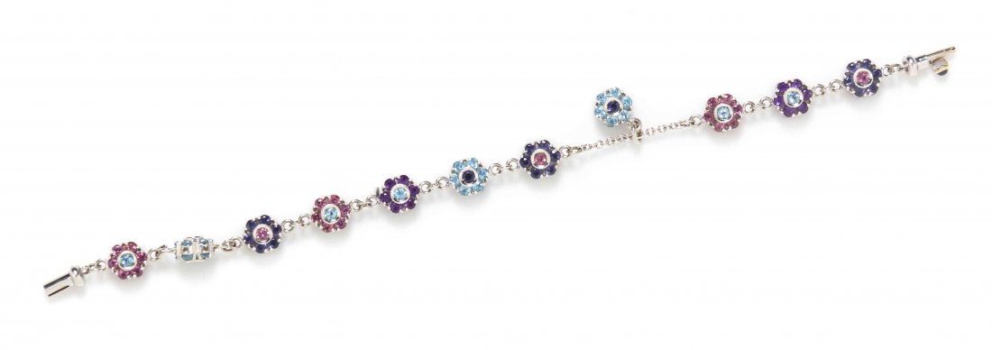An 18 Karat White Gold, Iolite, Amethyst and Garnet: An 18 Karat White Gold, Iolite, Amethyst and Garnet Bracelet, consisting of 10 fleurette design links containing numerous round brilliant cut pink garnets, blue topaz and iolites in an alternating pat