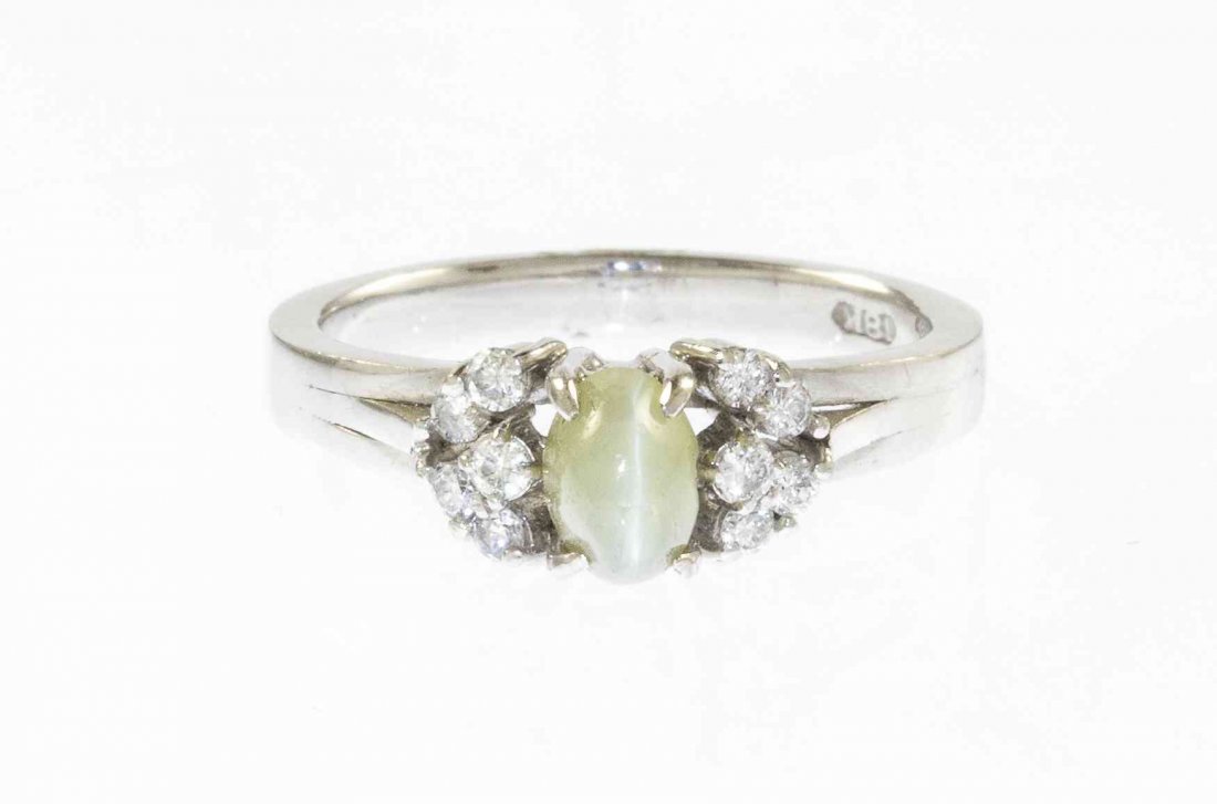 An 18 Karat White Gold, Cat's Eye and Diamond Ring,: An 18 Karat White Gold, Cat's Eye and Diamond Ring, containing one oval cabochon cut cat's eye measuring approximately 6.18 x 4.34 x 4.60 mm and ten single cut diamonds weighing approximately 0.10 car