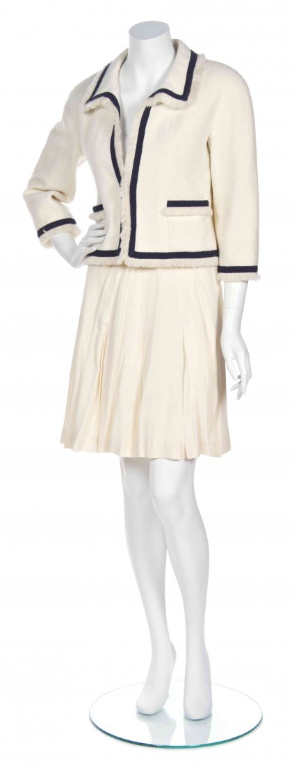 A Chanel Cream Boucle Jacket, Size 36.: A Chanel Cream Boucle Jacket, Collection 28, comprised of an open front jacket with two square pockets, braided navy trim, ivory fringe and chainweighted hem together with an inverted pleat skirt. Lab