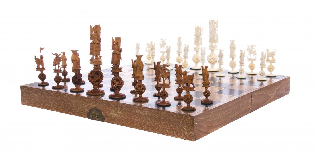A Chinese Carved Ivory Chess Set, Height of tallest: A Chinese Carved Ivory Chess Set, comprising 32 pieces, one set tea stained, with fitted gameboard. Height of tallest piece 6 1/4 inches.