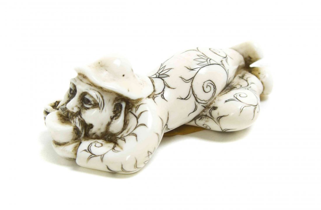 A Carved Ivory Netsuke of a Foreigner, Width 2 1/4: A Carved Ivory Netsuke of a Foreigner, the figure depicted recumbent and drinking from a teacup, having inlaid eyes. Width 2 1/4 inches. Property from the Collection of Dr. J. Don Nelson, Fargo, North