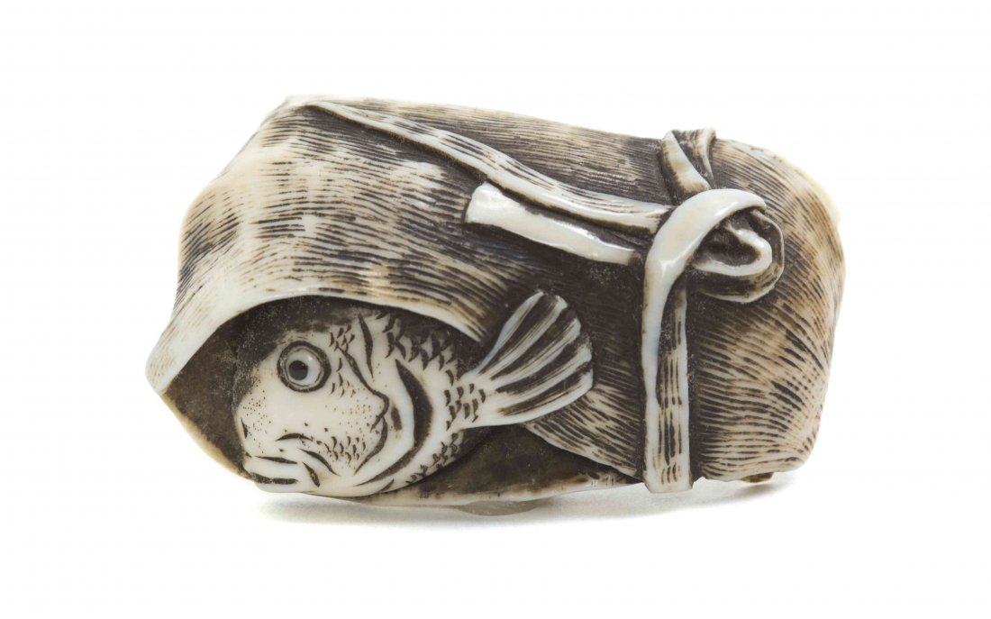 A Carved Ivory Netsuke of a Fish Wrapped in a Leaf,: A Carved Ivory Netsuke of a Fish Wrapped in a Leaf, the fish face peaking out from within a folded and tied banana leaf, signed. Width 2 3/8 inches. Property from the Collection of Dr. J. Don Nelson, 