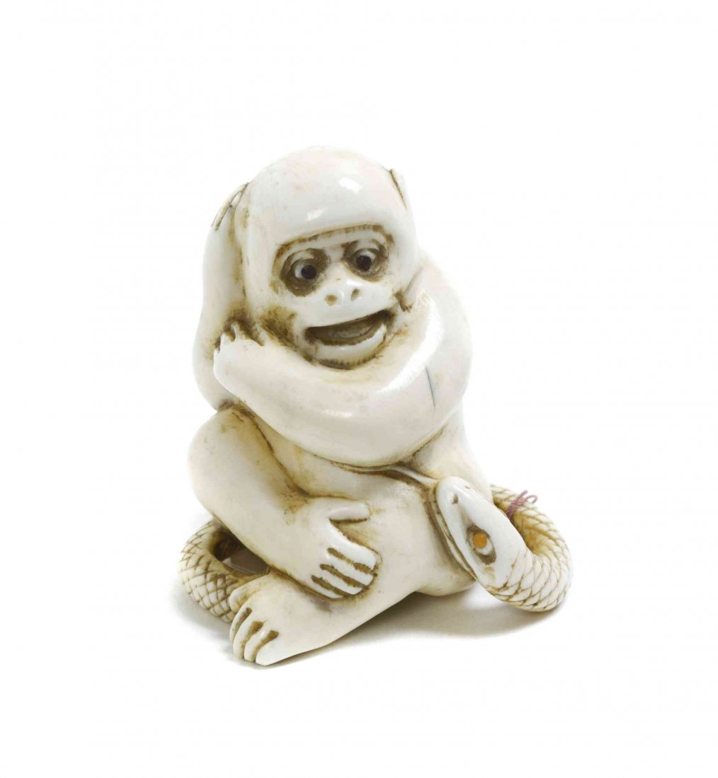A Carved Ivory Monkey and Snake Netsuke, Height 2: A Carved Ivory Monkey and Snake Netsuke, each creature having inlaid eyes, the monkey depicted seated and fearful of the coiled snake. Height 2 inches. Property from the Collection of Dr. J. Don Nelso