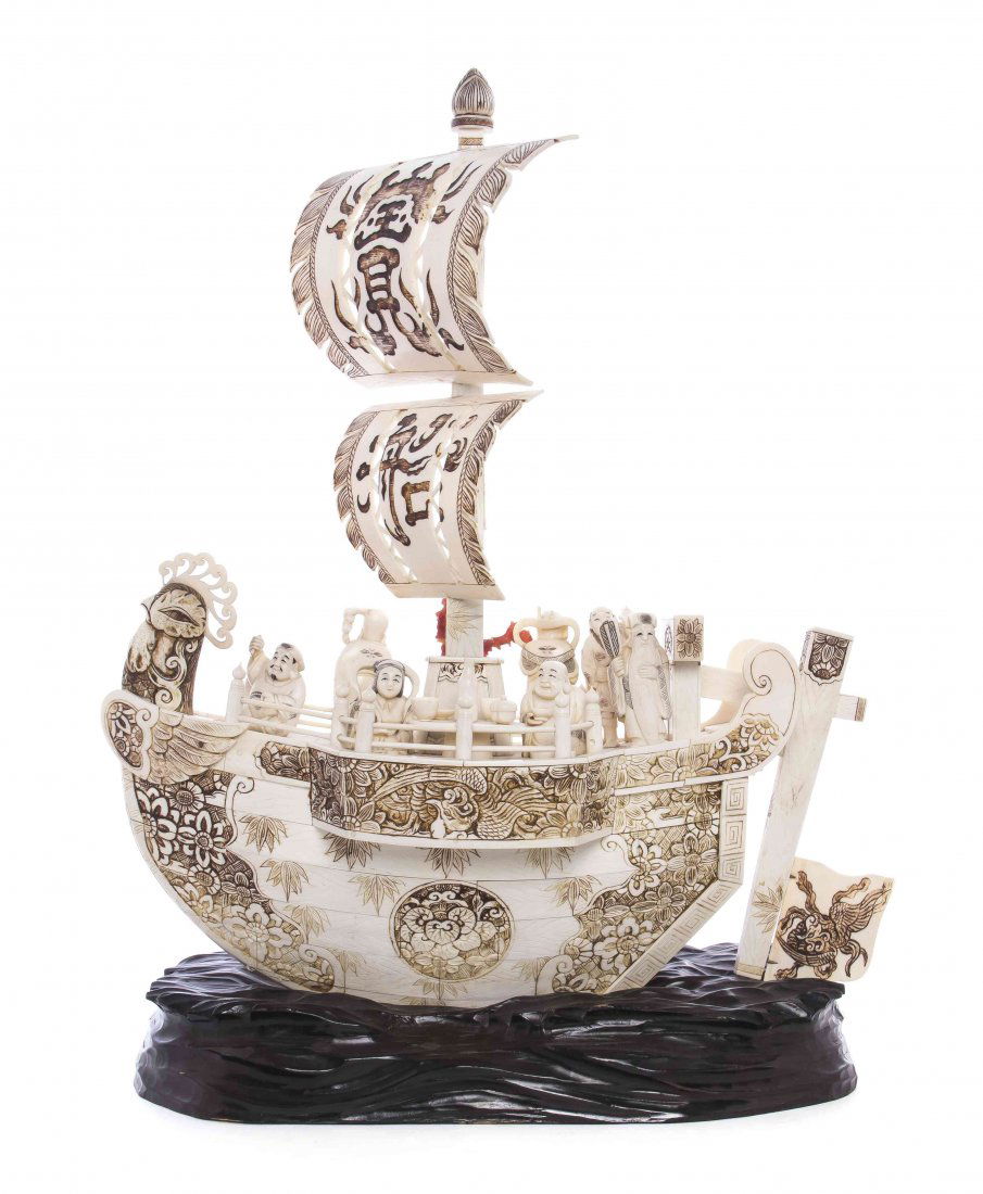A Japanese Carved Ivory Chicken Boat, Height 21 x width: A Japanese Carved Ivory Chicken Boat, having wood grain painted throughout the vessel, with the eight immortals depicted on deck bearing their traditional attributes, the sails inscribed 'Treasure Boa