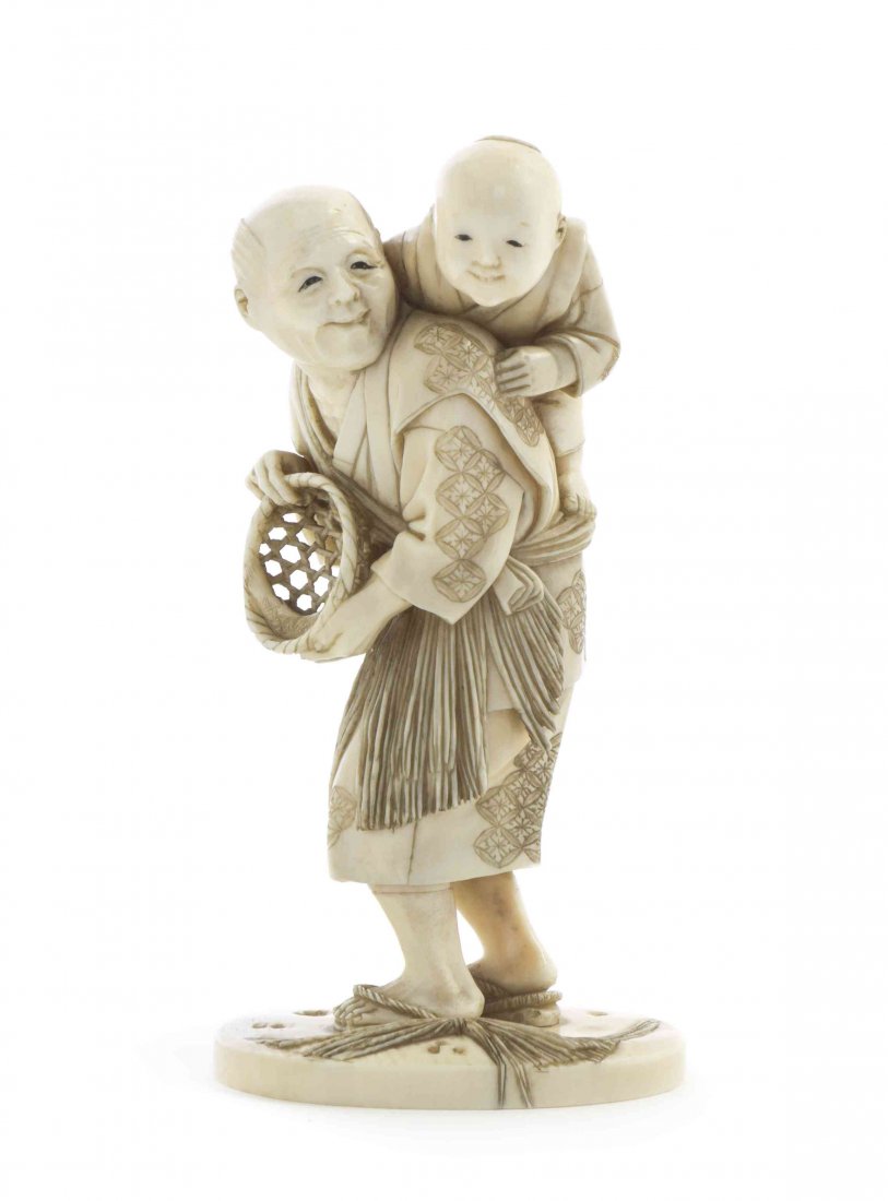 A Japanese Carved Ivory Okimono, Height 3 7/8 inches.: A Japanese Carved Ivory Okimono, depicting a man with a basket of fish and a boy on his back, the composition on an oval base of naturalistic carving, signed to the base. Height 3 7/8 inches. Property
