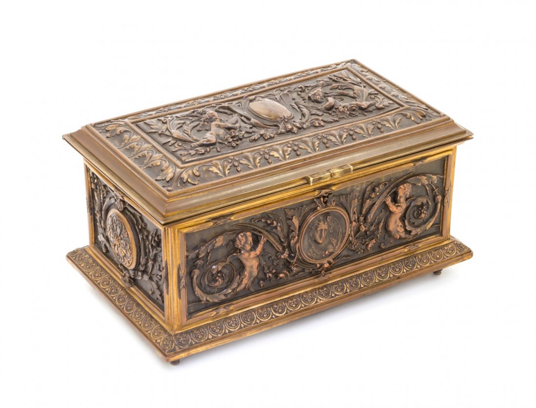 A Neoclassical Gilt Metal Casket, Width 8 5/8 inches.: A Neoclassical Gilt Metal Casket, having a rectangular hinged lid with a monogrammed cartouche, opening to a vacant padded interior, decorated with putti, foliate scrolls, and bellflowers, raised on t
