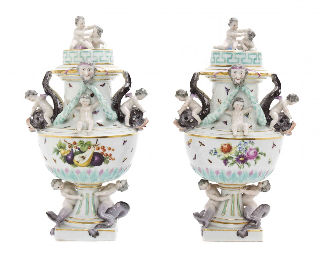 A Pair of Meissen Porcelain Covered Urns, Height 11: A Pair of Meissen Porcelain Covered Urns, each with a circular lift-off cover surmounted by a putto finial above a shaped body painted to show insects, floral sprays and fruit, further modeled to show