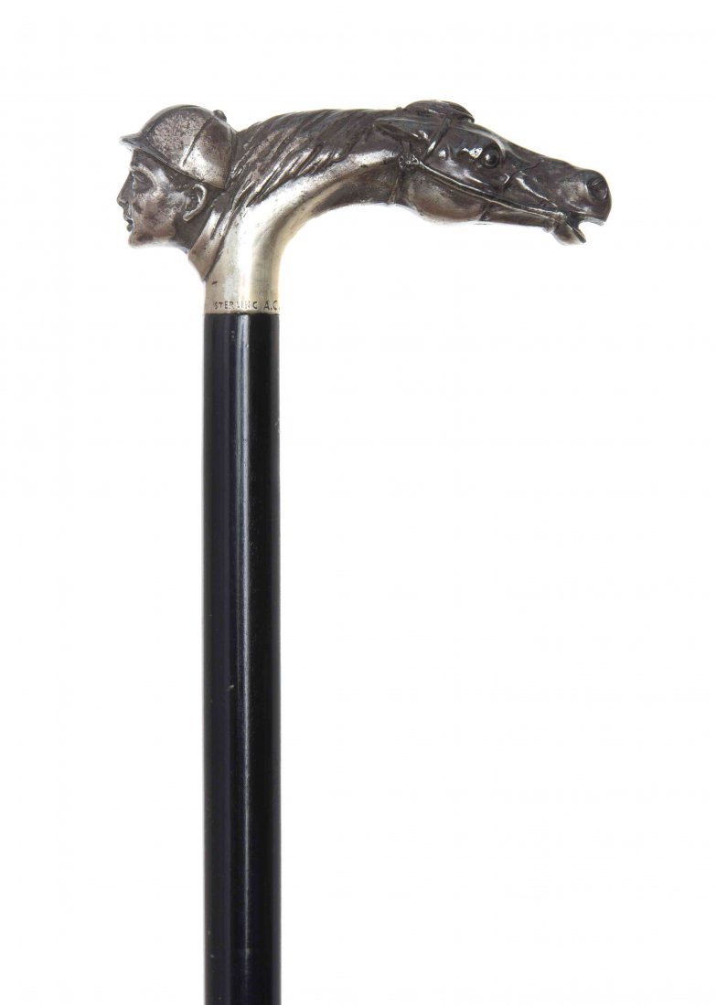 An American Sterling Silver Handled Cane, Length of: An American Sterling Silver Handled Cane, circa 1920's, having a tau shaped handle shaped as a horse head opposite a jockey head, stamped Sterling A.C., having an ebonized shaft ending in a horn tip. 