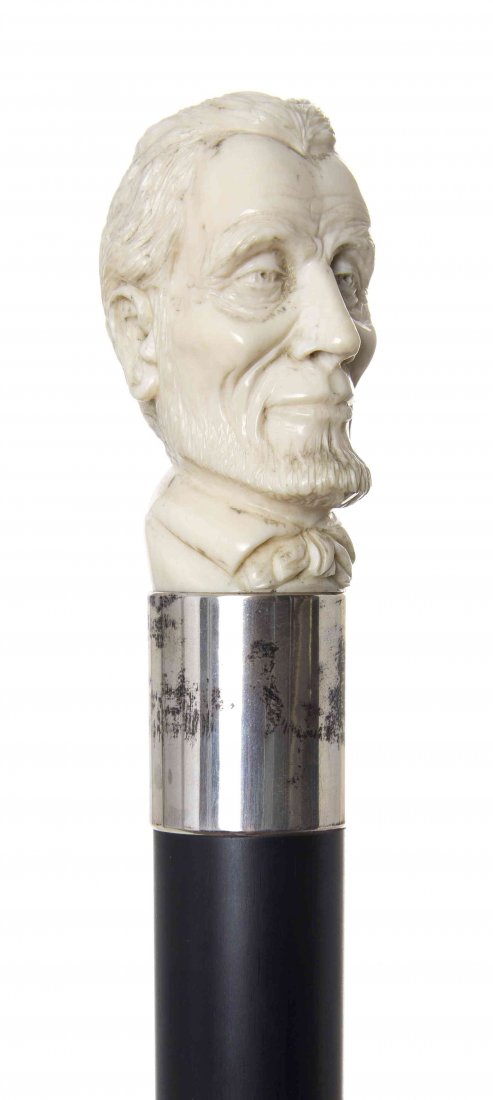An American Ivory Handled Walking Stick, Length of: An American Ivory Handled Walking Stick, late 19th century, having a carved handle depicting a bust of Abraham Lincoln, with a sterling silver collar and an ebony shaft, ending in a sterling silver fe