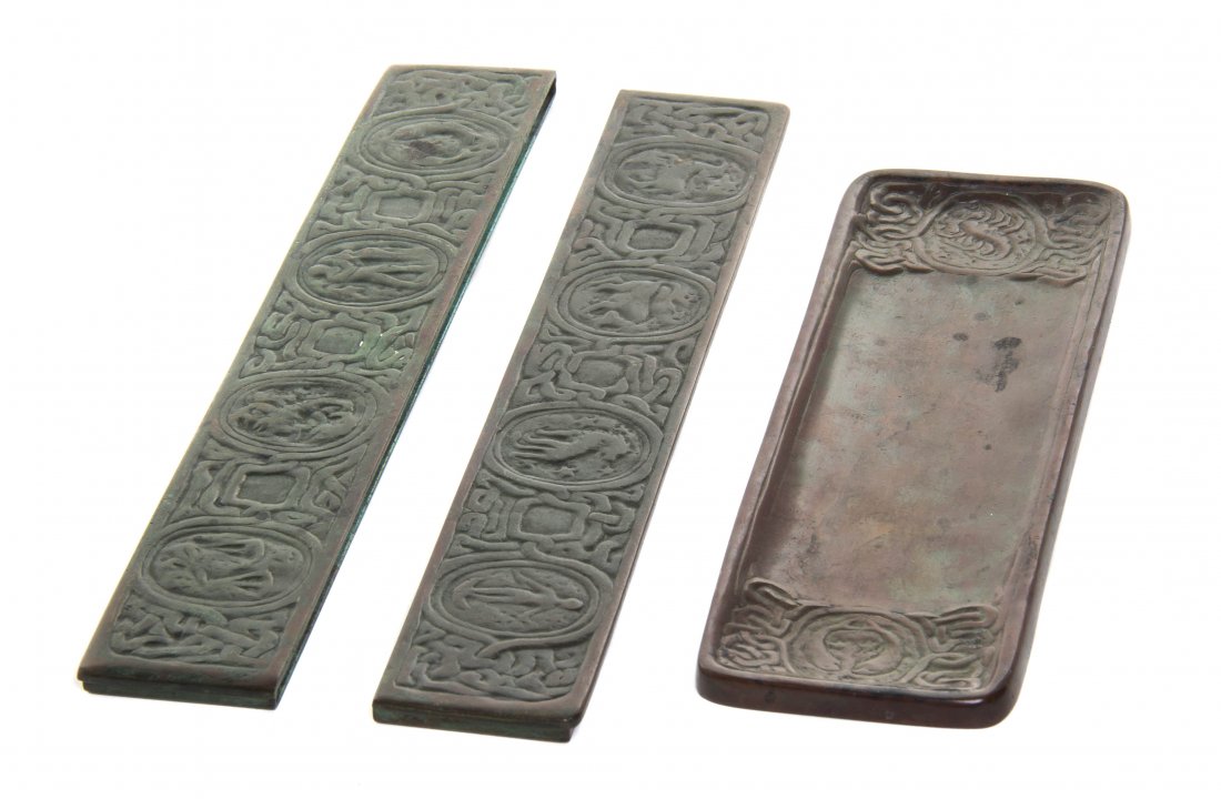 A Tiffany Studios Patinated Bronze Desk Set, Width of: A Tiffany Studios Patinated Bronze Desk Set, in the Zodiac pattern, comprising two blotter ends (994) and a pen tray (1000), each stamped Tiffany Studios New York with pattern number. Width of pen tra