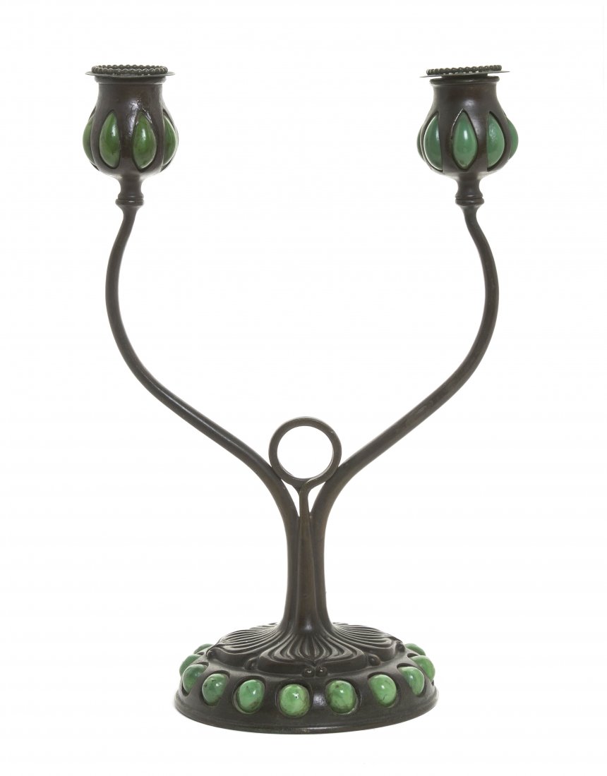 A Tiffany Studios Patinated Bronze and Favrile Glass: A Tiffany Studios Patinated Bronze and Favrile Glass Two-Light Candelabrum, having two baluster form candle cups with blown-out green glass above the shaped cylindrical standard, raised on a circular 