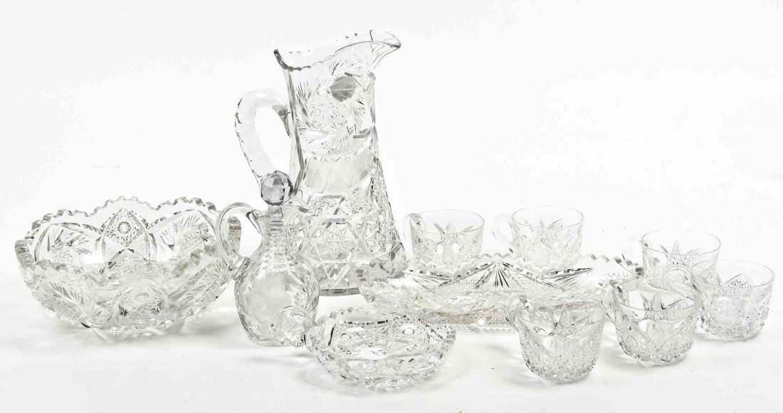 A Collection of Cut Glass Table Articles, Height of: A Collection of Cut Glass Table Articles, comprising a center bowl, a water pitcher, six cups, a cruet, a celery tray and a nappy. Height of first 6 1/2 inches. Property from the Collection of Ed and 