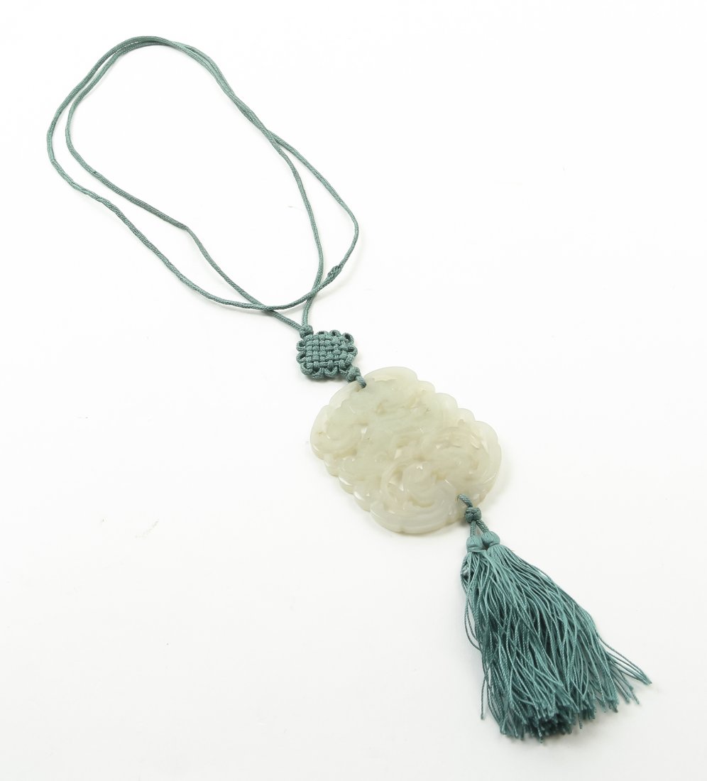 A Carved Jade Pendant, Height 2 1/8 inches.: A Carved Jade Pendant, of a pale celadon colored stone depicting a bat over a stylized lingzhi fungus and confronting sinuous qilong, strung on a silk cord with tassel. Height 2 1/8 inches.
