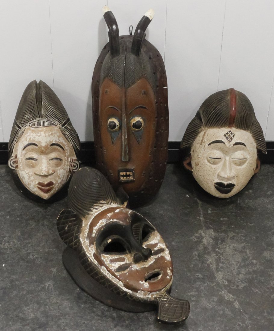 Four African Carved Masks, Height of tallest 21 inches.: Four African Carved Masks, comprising Baule and Punu examples, two with closed eyes and white pigmentation, one with iron red and white pigmenation and one with an elongated face and horns. Height of 