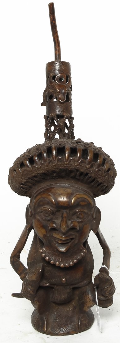 A Bamileke Bronze Figural Pipe, Height 17 inches.: A Bamileke Bronze Figural Pipe, depicting a seated man with an object in each hand. Height 17 inches. Property from the Collection of Gerald F. Glaeve, Mount Horeb, Wisconsin