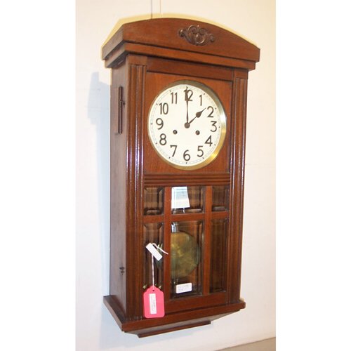 MAHOGANY MISSION-STYLE WALL CLOCK: Dome-shaped top over Mission-style one-door case, porcelain dial, with keys & pendulum. H: 28, w: 13, d: 7 in.