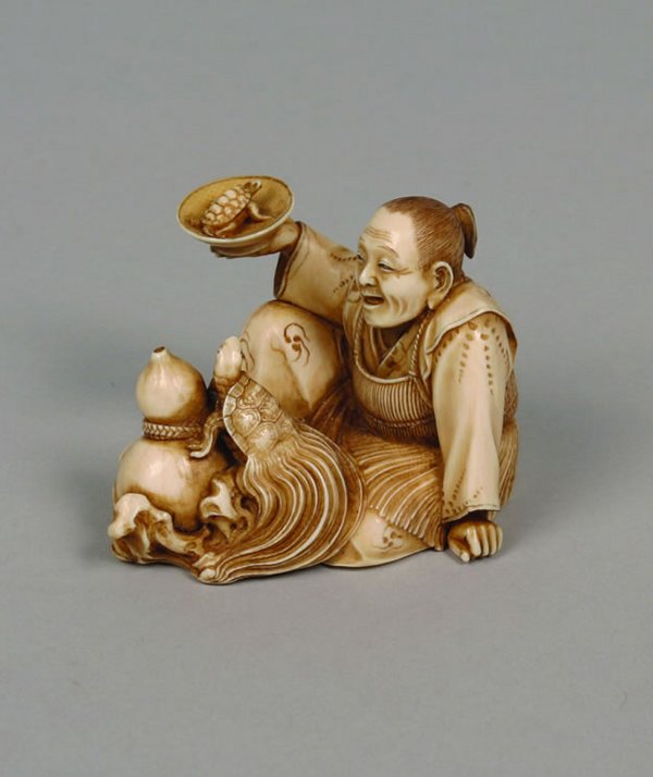 A Japanese Carved Ivory Okimono,: A Japanese Carved Ivory Okimono, depicting an old man seated next to a turtle and a gourd, holding a small turtle on a plate, the base inscribed with two characters. Height 1 3/4 inches.Property of Ch