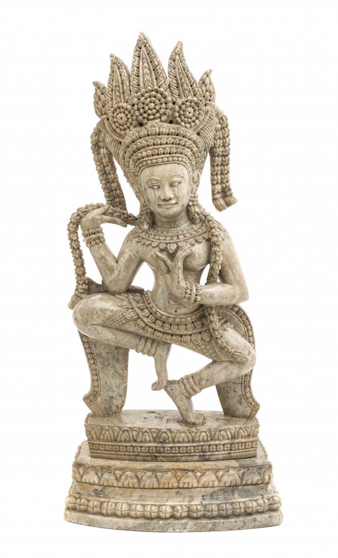 A Carved Soapstone Figure of a Deity, Height 16 inches: A Carved Soapstone Figure of a Deity, depicted dancing, with a headdress and adorned body, raised on a carved plinth base. Height 16 inches x width 7 x depth 3 1/2 inches.