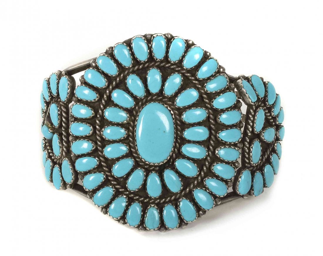A Navajo Silver and Turquoise Cluster Bracelet, Laura: A Navajo Silver and Turquoise Cluster Bracelet, Laura Moses Begay, having two rings of teardrop shaped stones surrounding oval center stone, flanked by fan shaped devices, signed L.M.B.. Length 5 1/4 