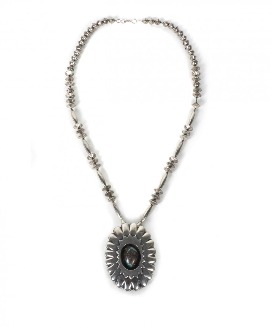 A Southwestern Shadow Box Pendant, Length of chain 28: A Southwestern Shadow Box Pendant, having a large turquoise cabochon inside a lobed pendant with stylized petal casing and bale mount, on a mixed tube and melon bead necklace, stamped M.M. Length of c