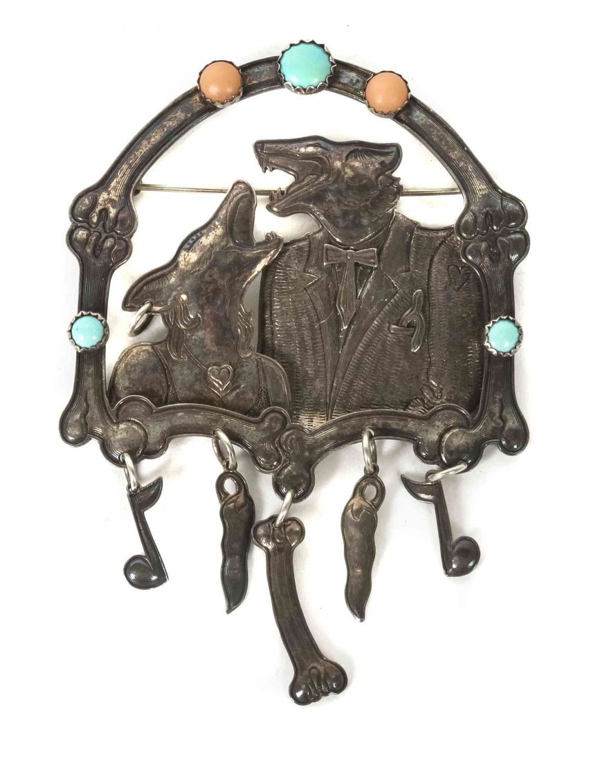 A Kit Carson Brooch, Height 2 3/4 x width 2 inches.: A Kit Carson Brooch, depicting two singing coyotes framed by a surround comprising dog bones, jewels, musical notes and chili peppers. Height 2 3/4 x width 2 inches.