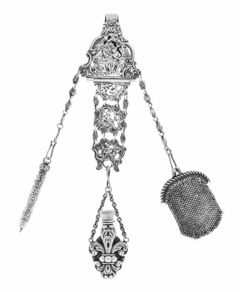 A German Silver Chatelaine, Georg Roth & Co., Hanau,: A German Silver Chatelaine, Georg Roth & Co., Hanau, Circa 1900, the clip cast with Classical figures and putti surrounded by rococo scrollwork from which a pencil case, mesh bag and fleur-de-lis-form