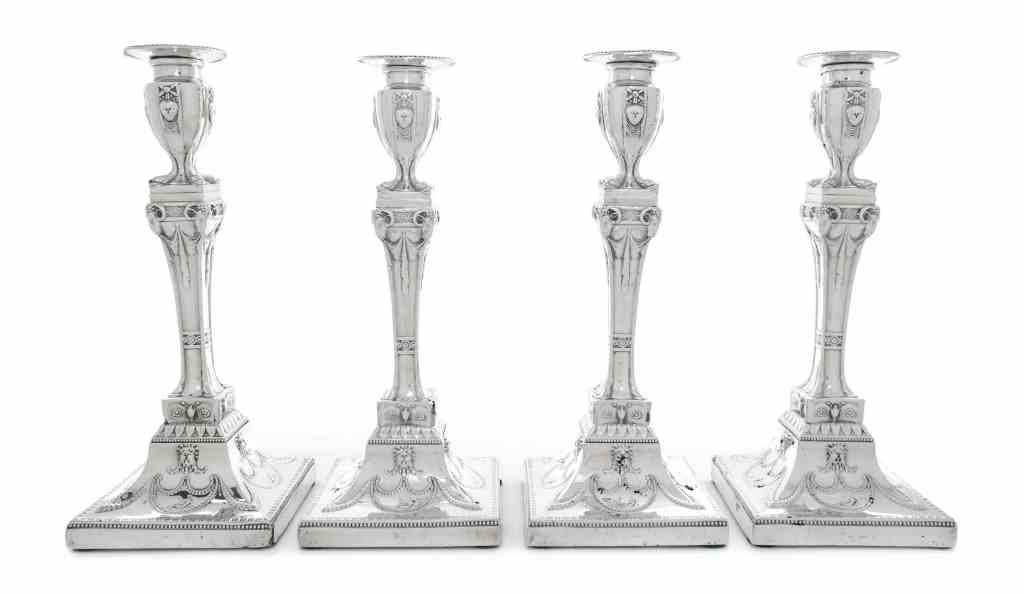 Four George V Silver Candlesticks, Birmingham, Ellis: Four George V Silver Candlesticks, Birmingham, Ellis Jacob Greenberg, 1913, the square bases with foliate swags and reclining figures rising to square stems decorated with drapery and rams heads, the