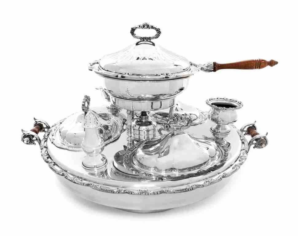 A Silver-Plate Dinner Service, 20th Century, Length: A Silver-Plate Dinner Service, 20th Century, the rotating circular stand fitted with three oval entree dishes, a central chafing dish, a caster and salt and associated sauce boat, all with scroll and 