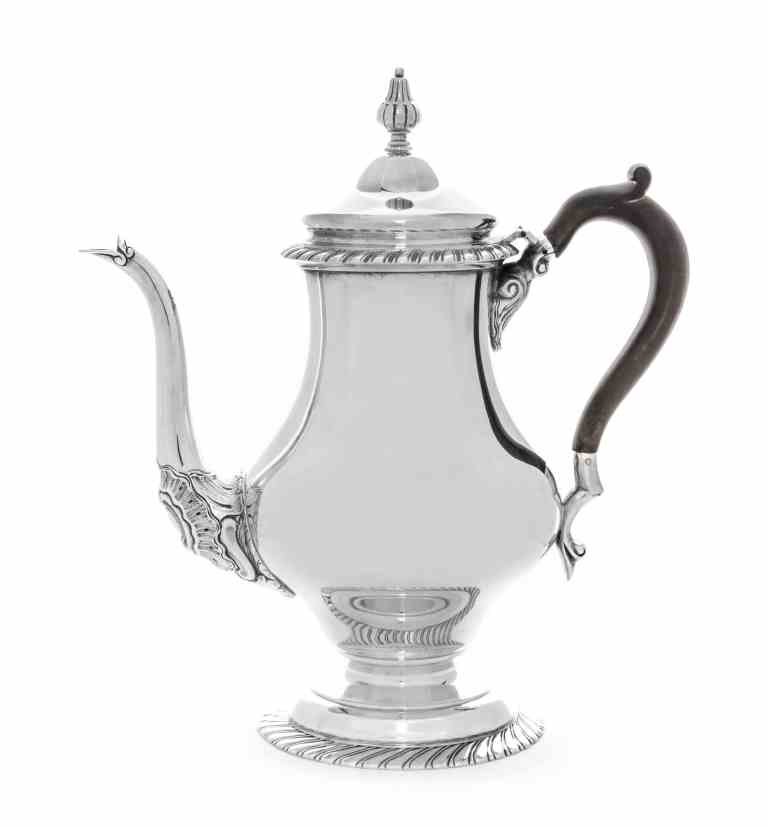 An American Silver Teapot, Tuttle Silversmiths, Boston,: An American Silver Teapot, Tuttle Silversmiths, Boston, 1923-29, in mid-18th century style, of baluster form with gadrooned borders, the lower spout decorated with rocaille, ebonized wood scroll handl