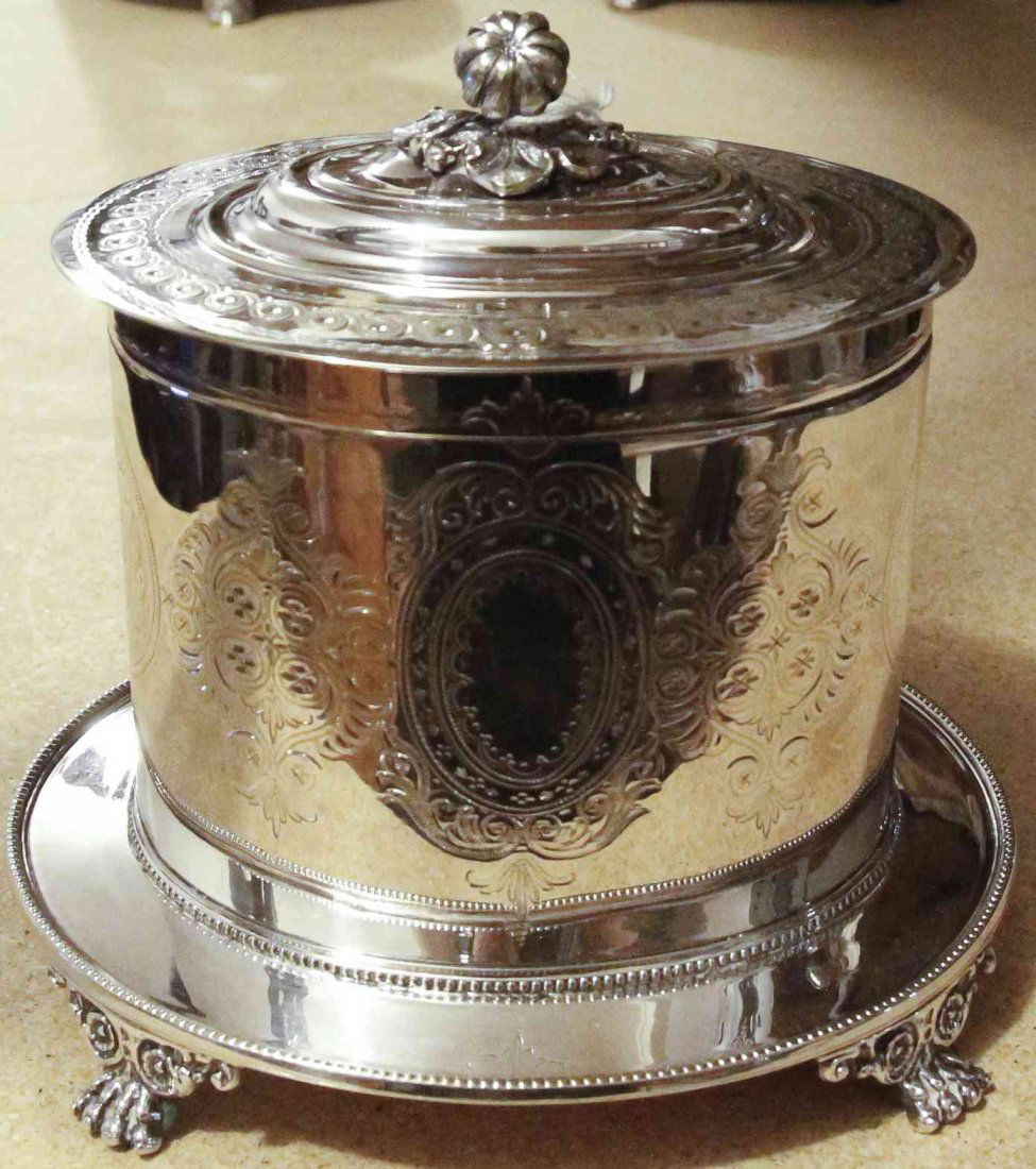 A Sheffield-Plate Biscuit Barrel on Stand, Mappin &: A Sheffield-Plate Biscuit Barrel on Stand, Mappin & Webb, Sheffield, Early 20th Century, of drum form engraved with foliage and medallions, on a fixed oval base raised on four paw supports, marked on