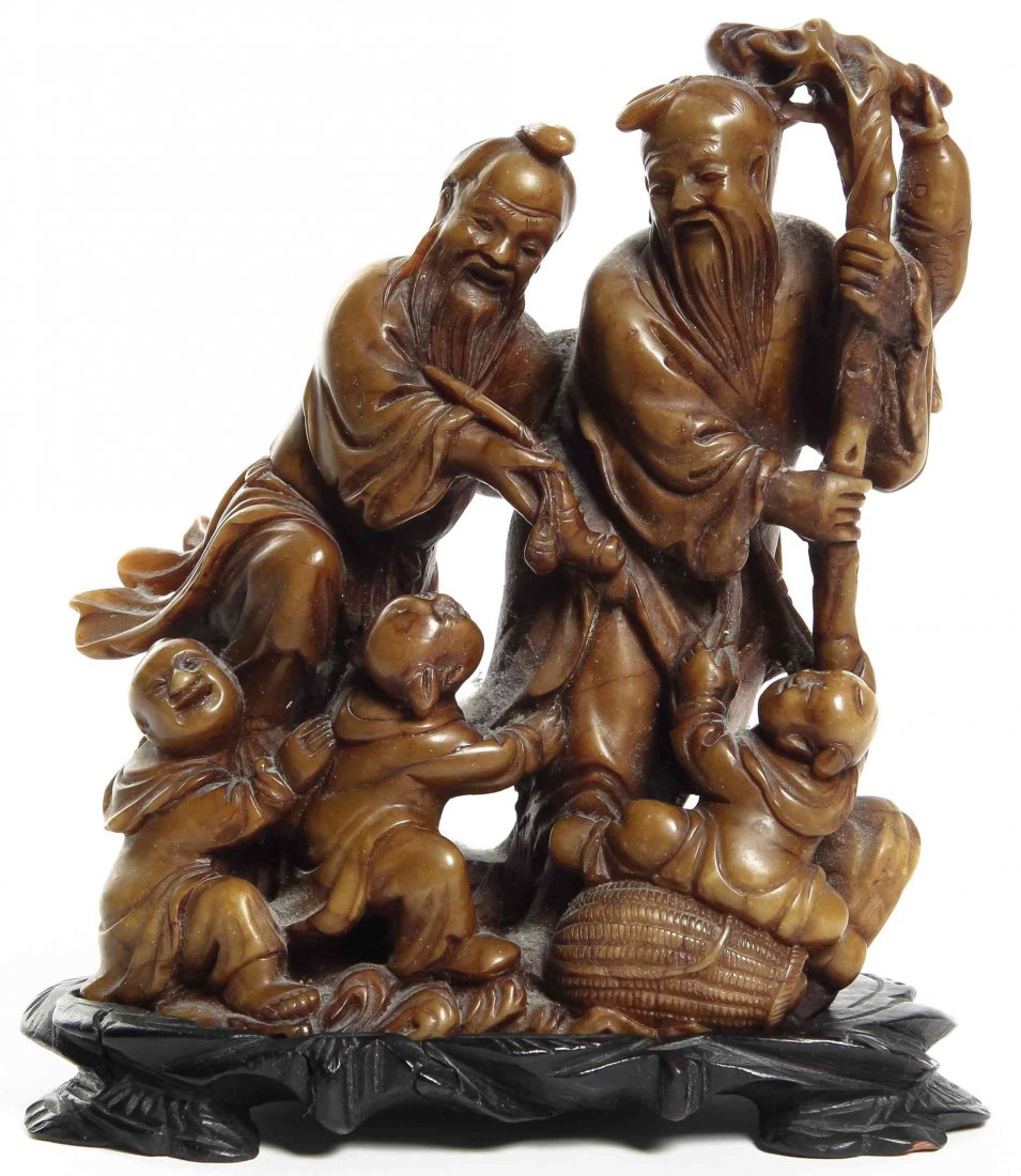 A Carved Soapstone Figural Group, Height 6 3/8 inches.: A Carved Soapstone Figural Group, depicting two robed sages with children clamering around them, raised on a wood base. Height 6 3/8 inches.