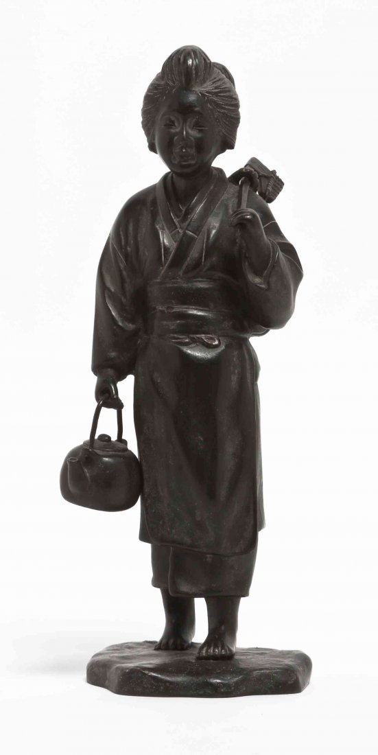 A Japanese Bronze Figure of a Lady, Height overall 12: A Japanese Bronze Figure of a Lady, depicted with a covered hatchet over her shoulder slung with a woven basket, carrying a tea kettle in the other hand, raised on a naturalistic base with oval signat