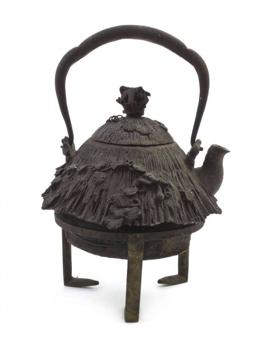 A Japanese Iron Teapot on Stand, Height overall 10 1/2: A Japanese Iron Teapot on Stand, having a surmounting arched handle, with raised naturalistic foliate decoration around the base of the vessel, marked to the underside. Height overall 10 1/2 inches.