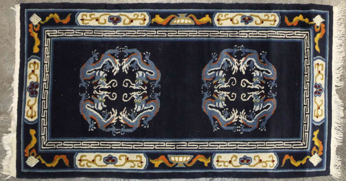 A Chinese Wool Rug, 5 feet 7 1/2 inches x 3 feet 1 1/2: A Chinese Wool Rug, having two medallions on a navy field, within multiple borders. 5 feet 7 1/2 inches x 3 feet 1 1/2 inches. Property from the Collection of a Lady, Oak Brook, Illinois