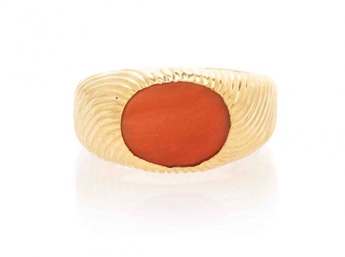 An 18 Karat Yellow Gold and Coral Ring, Schlumberger: An 18 Karat Yellow Gold and Coral Ring, Schlumberger for Tiffany & Company, containing one oval tablet cut pink-orange coral measuring approximately 13.75 x 11.15 mm within a fluted texture setting. S