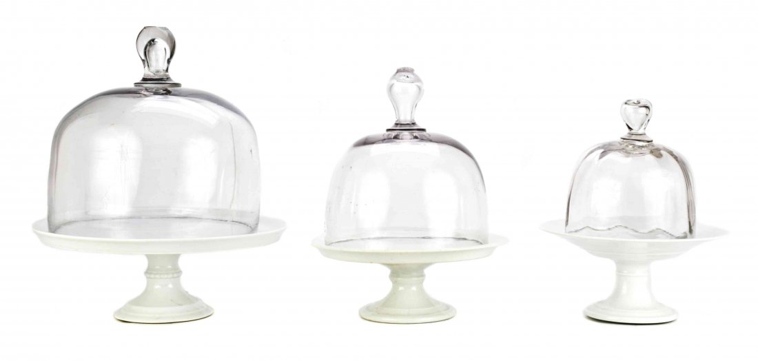 A Set of Three Continental Colorless Glass Cake Domes,: A Set of Three Continental Colorless Glass Cake Domes, one with molded prunt at handle, another with trapped air bubble handle, various sizes. Property of a Palm Beach Estate