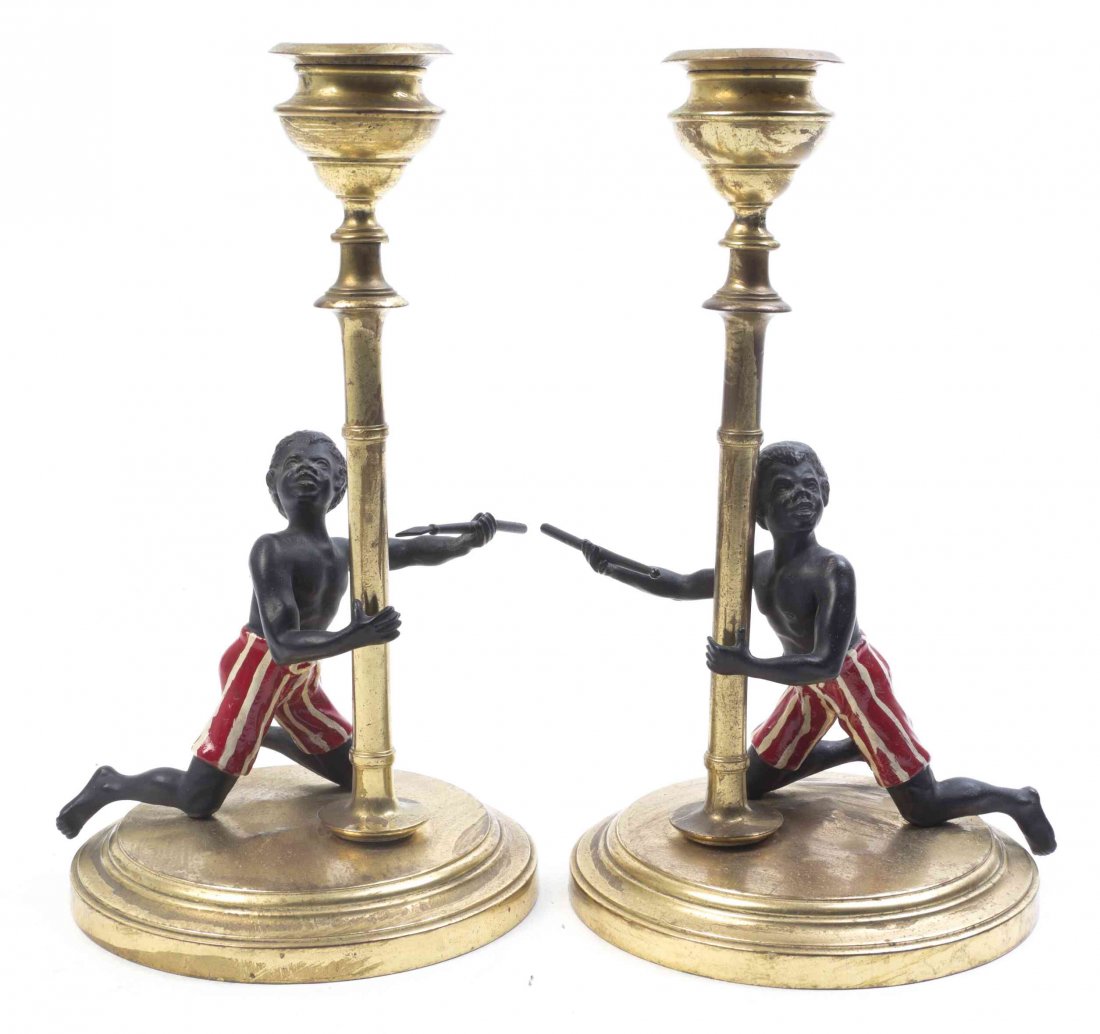 A Pair of Brass Mounted Blackamoor Candlesticks, Height: A Pair of Brass Mounted Blackamoor Candlesticks, each figure depicted kneeling and holding a spear. Height 7 1/4 inches.