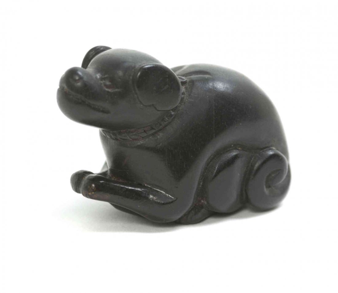 A Carved Ebony Netsuke of a Dog, Width at widest 1 7/8: A Carved Ebony Netsuke of a Dog, the beast depicted crouching, with round ears and a coiled tail, wearing a collar. Width at widest 1 7/8 inches. Property from the Collection of Dr. J. Don Nelson, Far