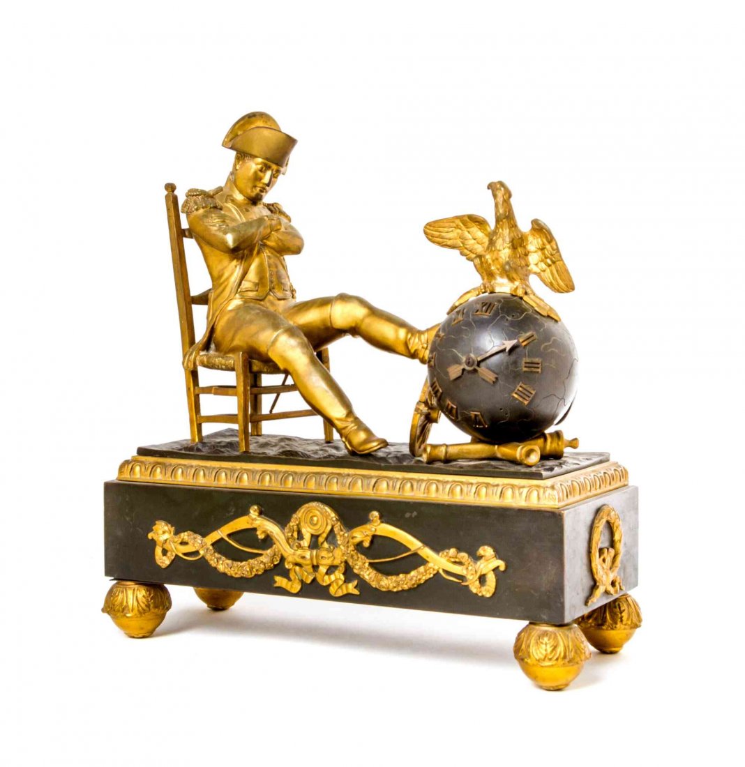 A French Gilt and Patinated Bronze Figural Mantel: A French Gilt and Patinated Bronze Figural Mantel Clock, modeled as a seated Napoleon, his left leg raised on the spherical clock barrel, set on a rectangular plinth base, having time only movement. W