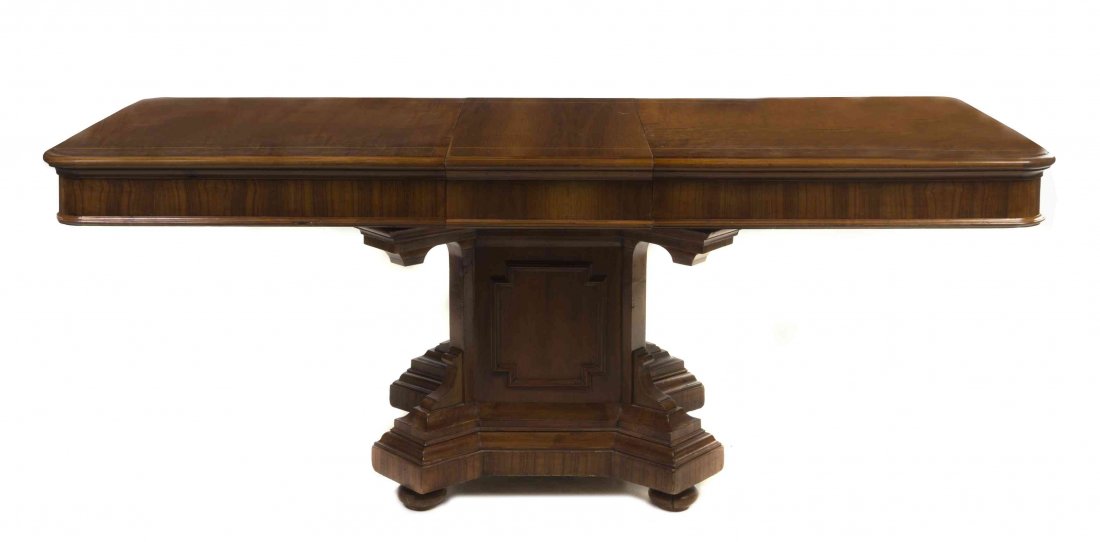 An Italian Walnut Dining Table, Height 33 1/2 x width: An Italian Walnut Dining Table, late 19th/early 20th century, having a rectangular top with rounded corners raised on a rectangular pedestal above a quadripartite base ending in flattened bun feet. He