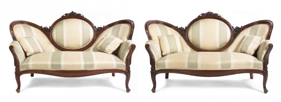A Pair of Victorian Mahogany Settees, Width 67 inches.: A Pair of Victorian Mahogany Settees, each having an undulating and floral carved crest rail enclosing a padded back and over a stuffover seat, raised on cabriole legs. Width 67 inches.