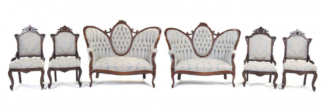 A Victorian Parlor Suite, Width of settees 54 inches.: A Victorian Parlor Suite, comprising two settees and four side chairs, each having a carved crest rail over the upholstered back and seat, raised on cabriole legs. Width of settees 54 inches.