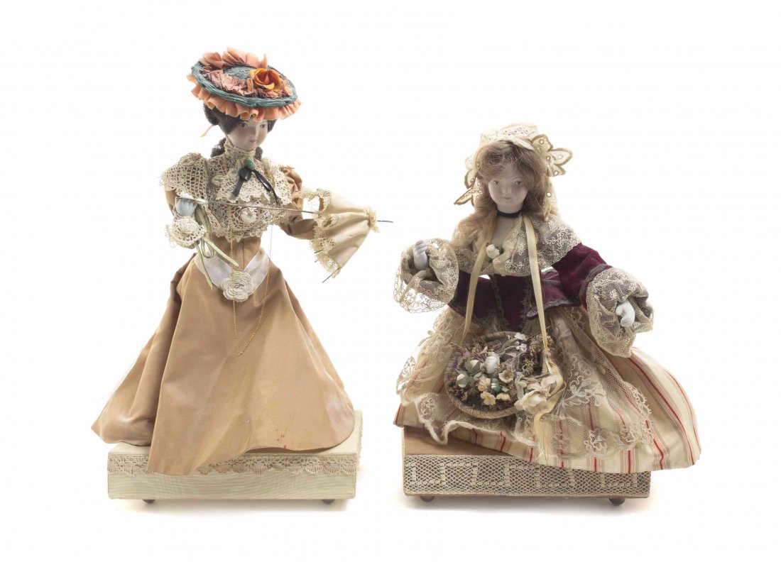 Two Continental Bisque Porcelain Faced Dolls, Height of: Two Continental Bisque Porcelain Faced Dolls, the first depicting a girl with a parasol, the second a girl with a basket of flowers, each set on musical bases. Height of taller overall 15 3/4 inches. 