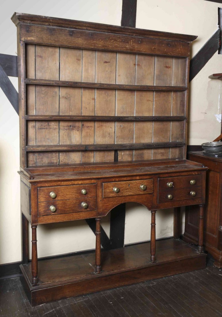 An Oak Welsh Cupboard in Two Parts, Height 82 x width: An Oak Welsh Cupboard in Two Parts, the superstructure having a molded cornice over three plate racks, the base having rectangular top over one shallow drawer over two deep drawers, raised on turned l