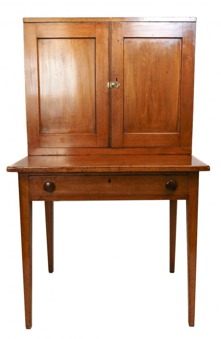 An American Maple Plantation Desk, Height 55 x width 33: An American Maple Plantation Desk, in two parts, the superstructure having two paneled doors opening to a fitted interior, the base with rectangular writing surface opening to a fitted drawer, raised 