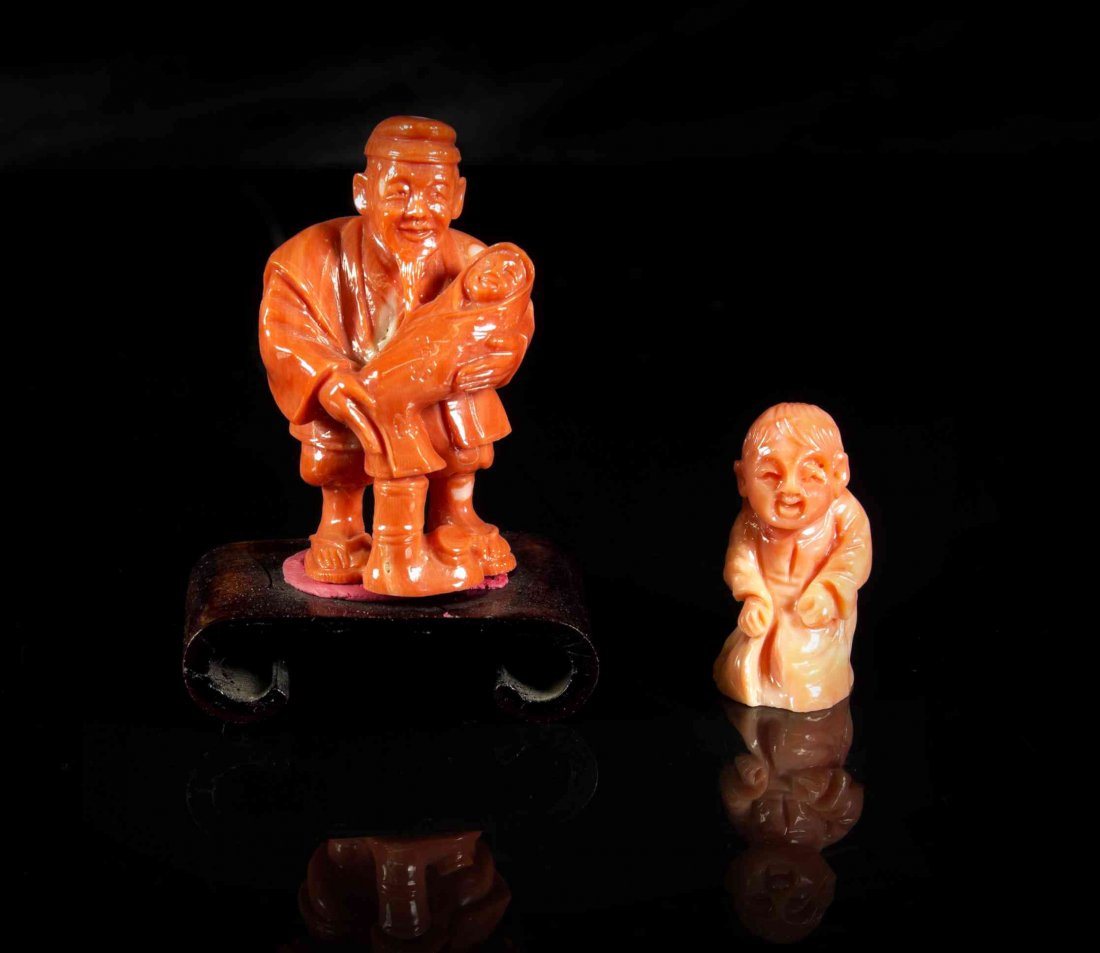 Two Carved Coral Figural Compositions, Height of taller: Two Carved Coral Figural Compositions, the first a Chinese figure of a boy, the second a Japanese netsuke depicting an elderly man holding a swaddled baby, raised on a scrolled wood stand. Height of t