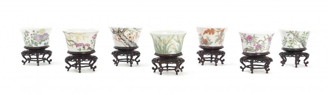 A Set of Seven Chinese Porcelain Tea Cups, Height 2: A Set of Seven Chinese Porcelain Tea Cups, Republic Period, having floral decoration on a white field, with carved hardwood stands. Height 2 inches. Property from the Estate of Virginia H. Rogers, Chi